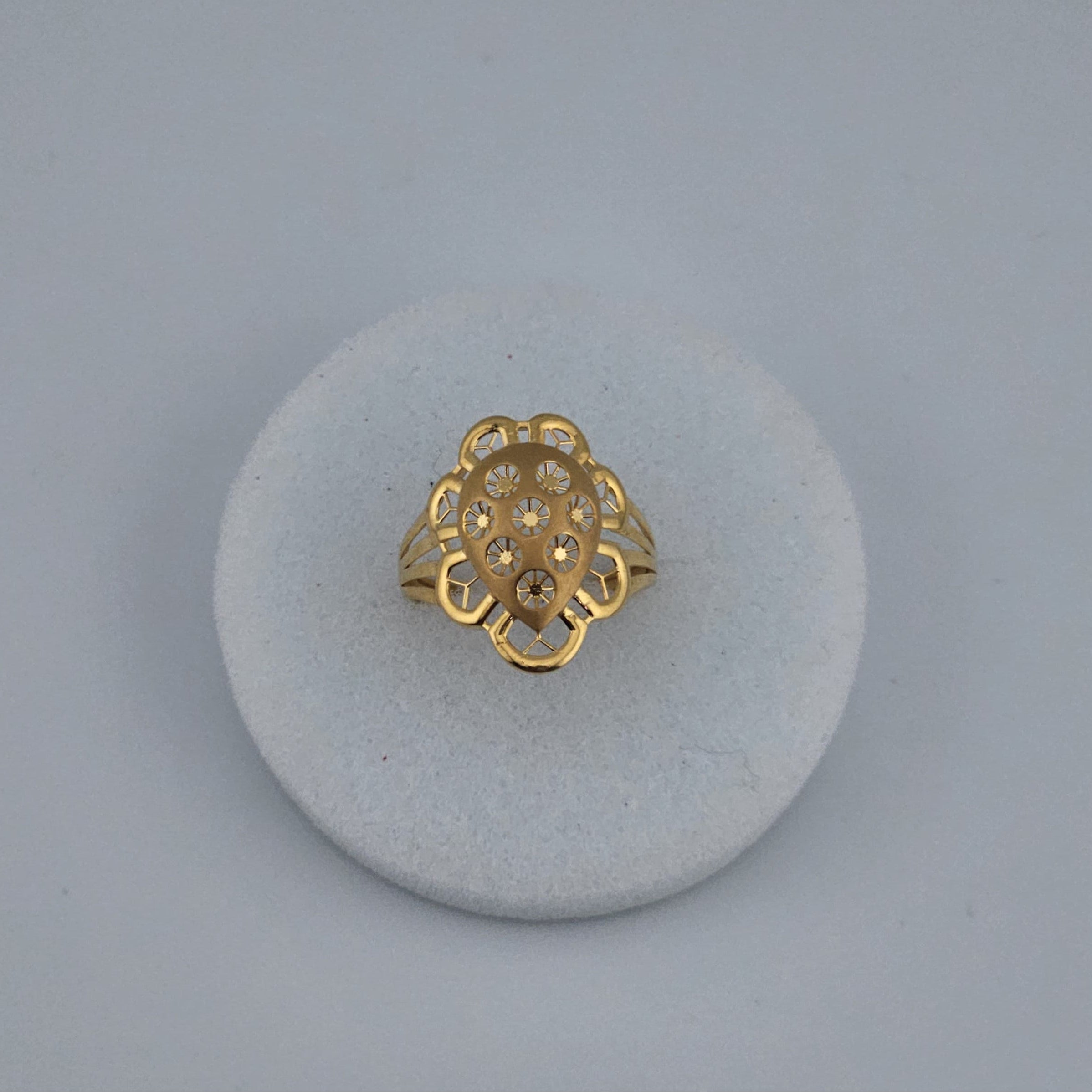 Gold ring with intricate design on a gray background